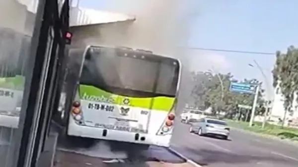 Autobús del Tuzobús con humo saliendo del motor, mientras usuarios evacuan frente a una estación en Pachuca.