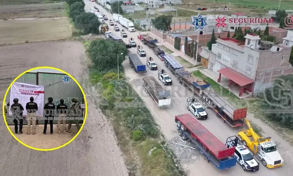 Agentes de seguridad resguardan los 33 vehículos de carga y maquinaria especializada asegurados durante el cateo en los límites de Mineral de la Reforma y Epazoyucan.